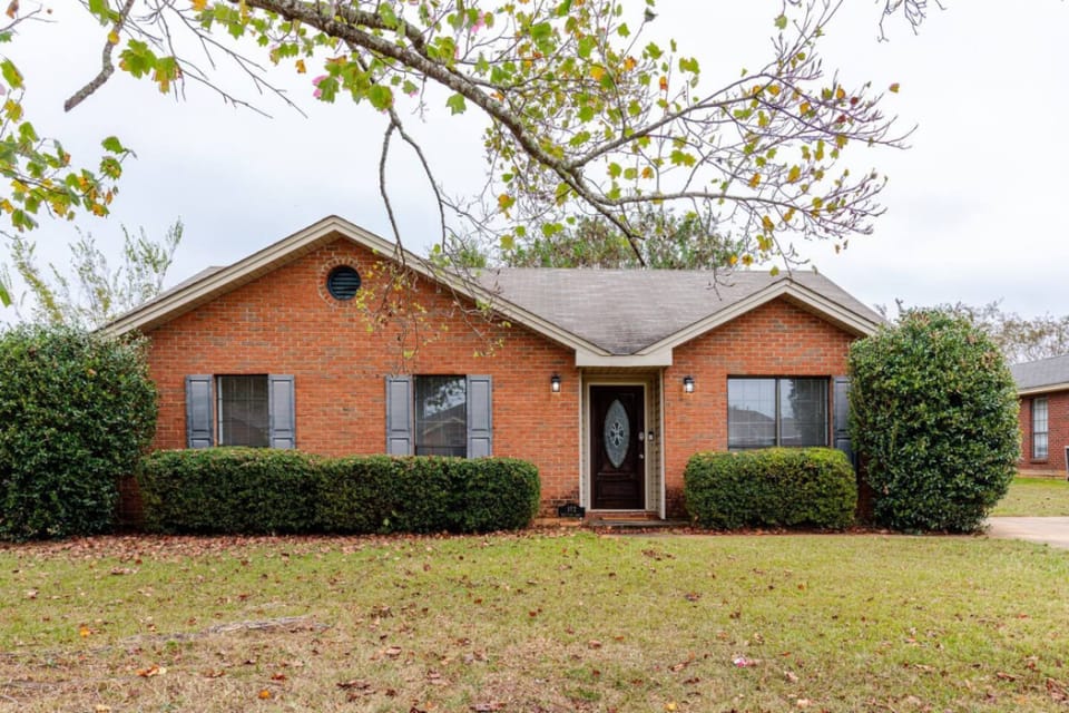 Whispering Oaks, a single-story brick home with a wide front lawn.