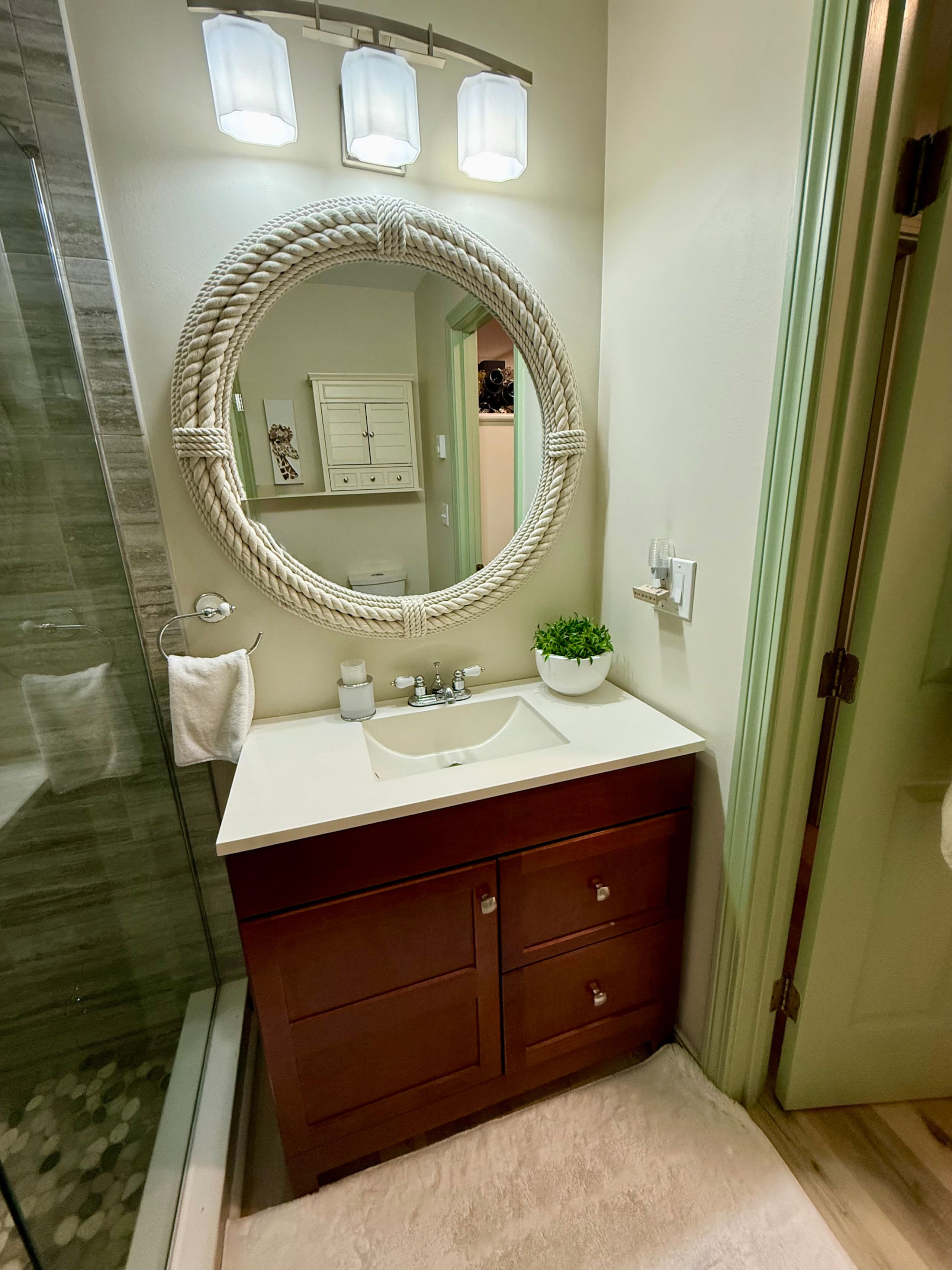 Full bathroom with round mirror and vanity