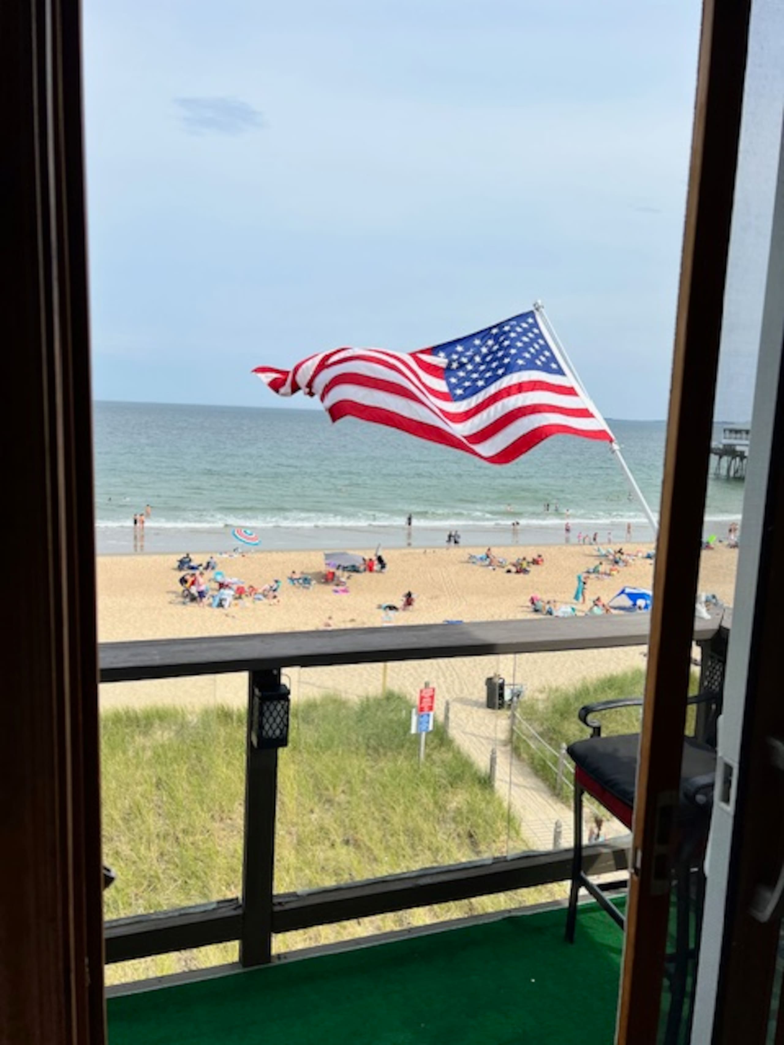 American flag on the balcony overlooking the crowded summer beach